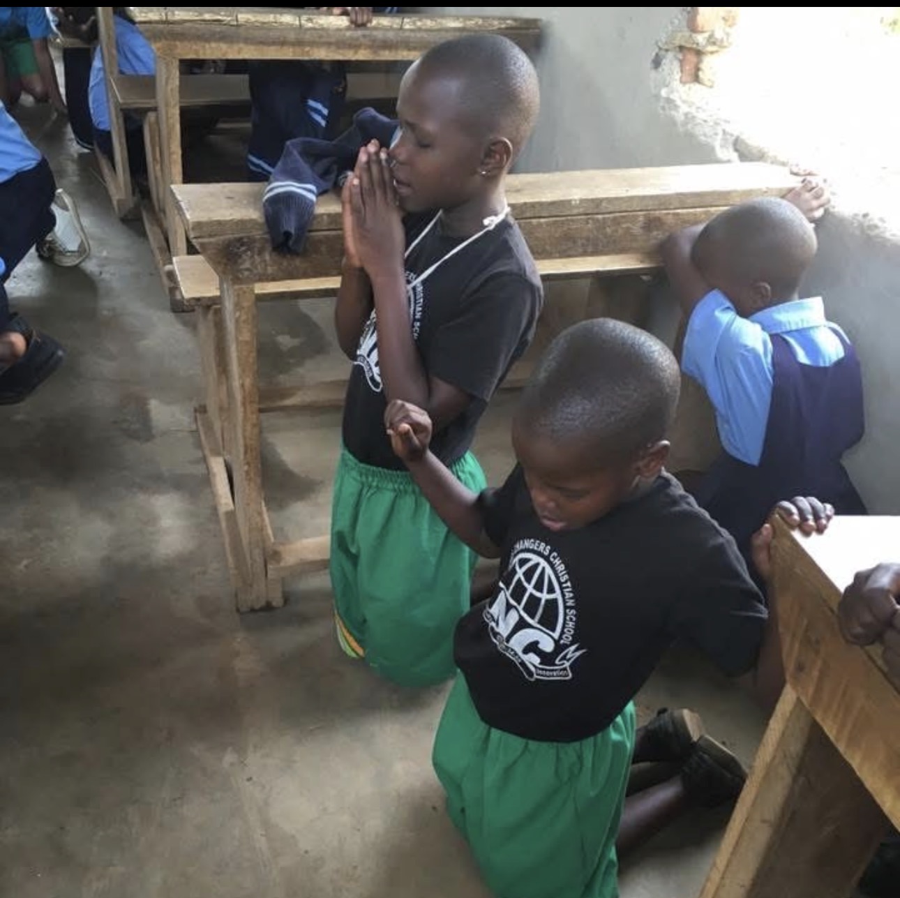 Nations' Changers students kneeling in prayer inside the classroom
