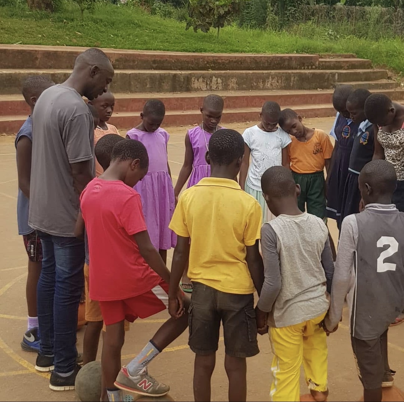 Coach and children praying in a circle on the court